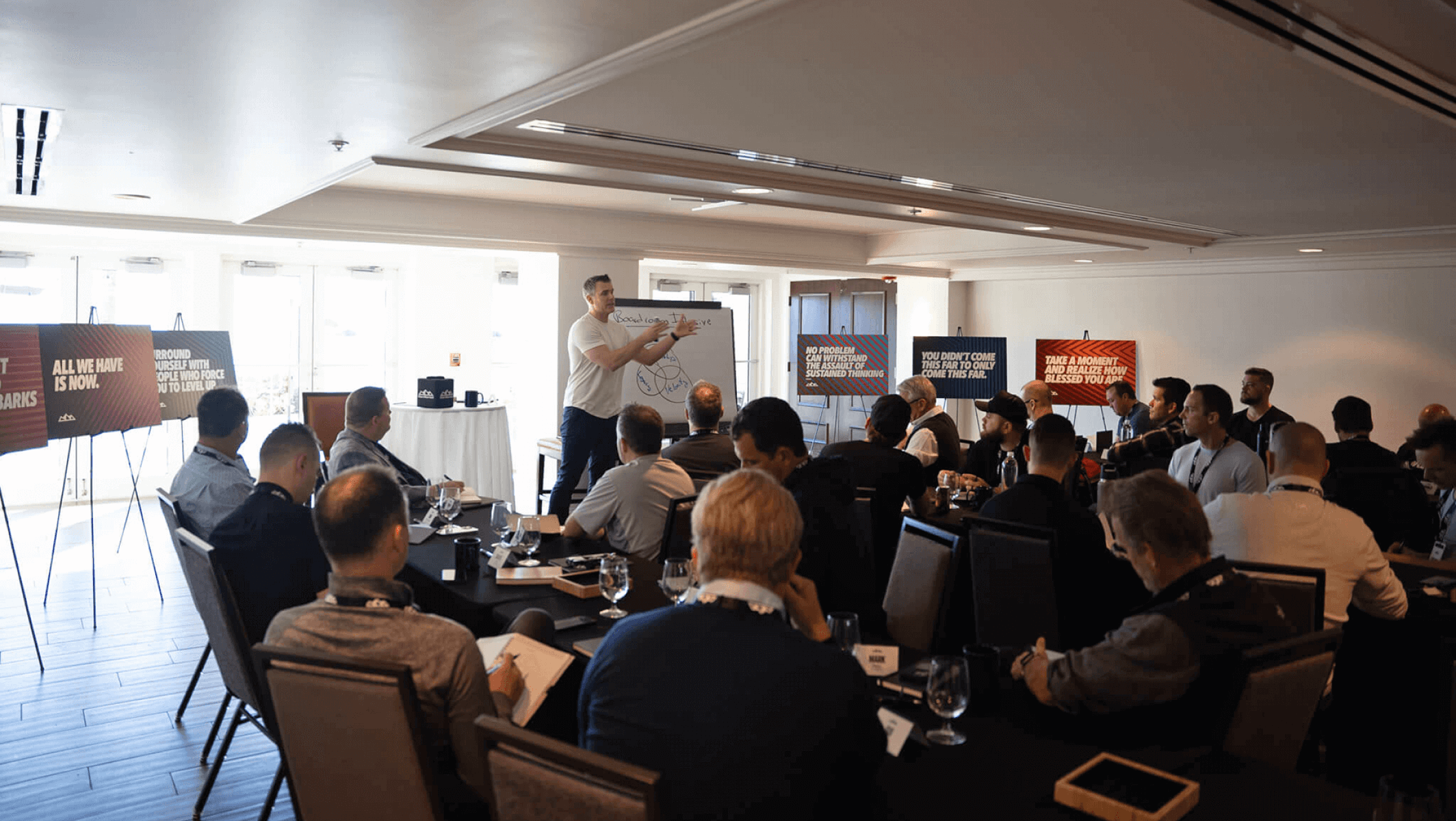 A man presents to attendees in a conference room