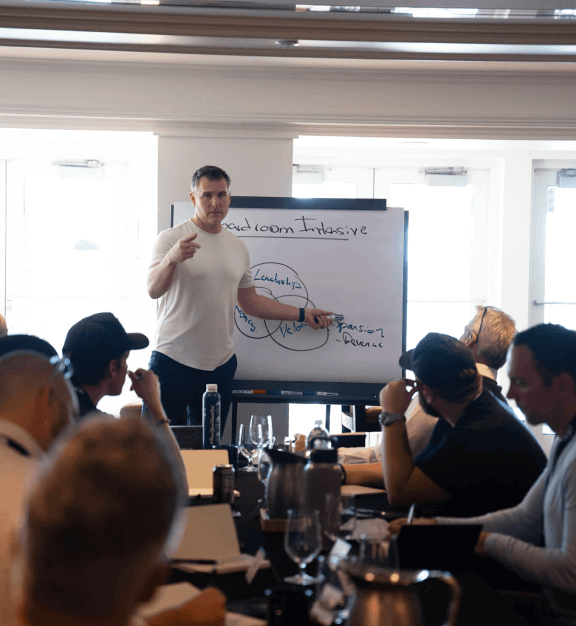 A man pointing at a whiteboard while addressing program attendees